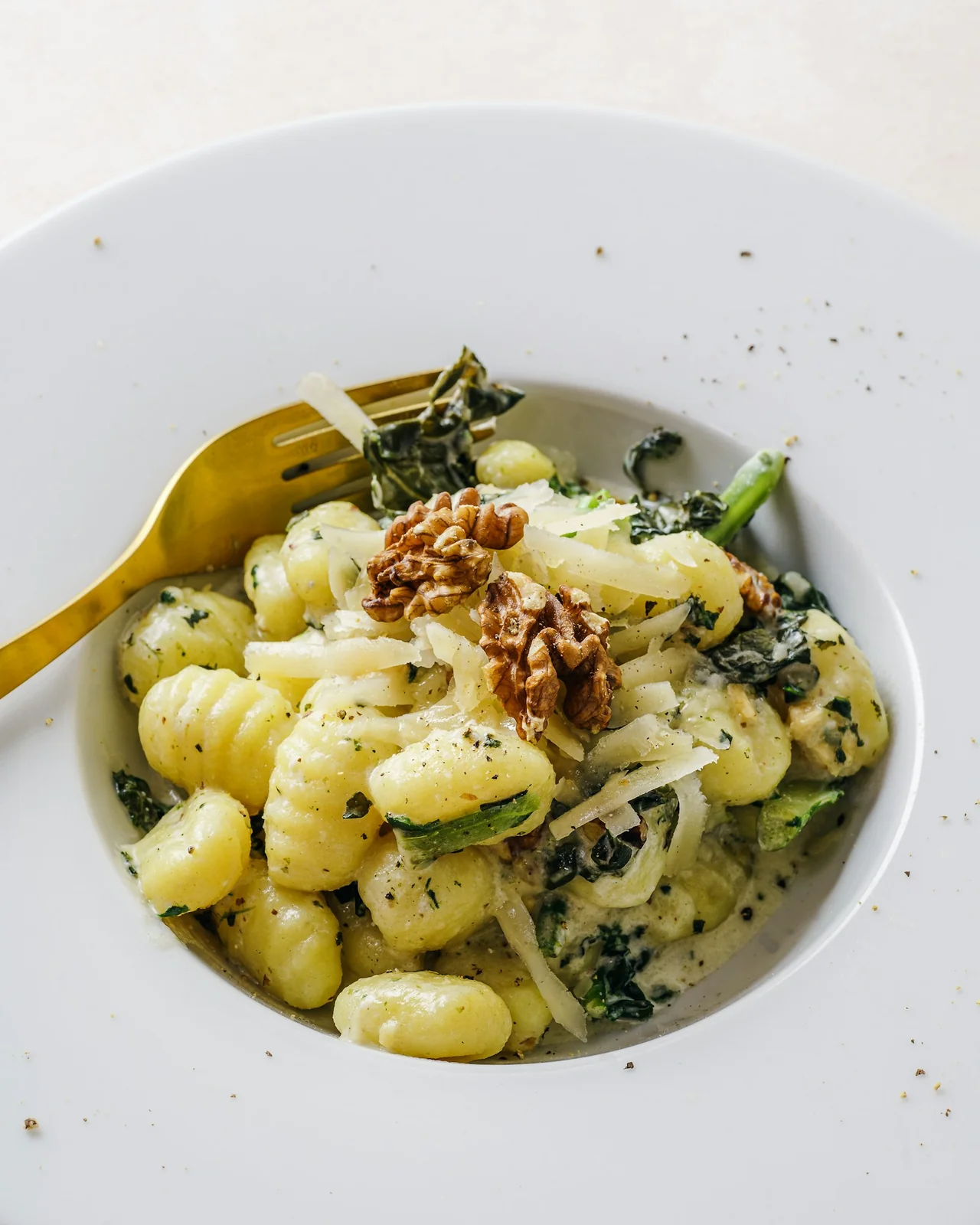 Gnocchi with greens and walnuts served on a ceramic plate